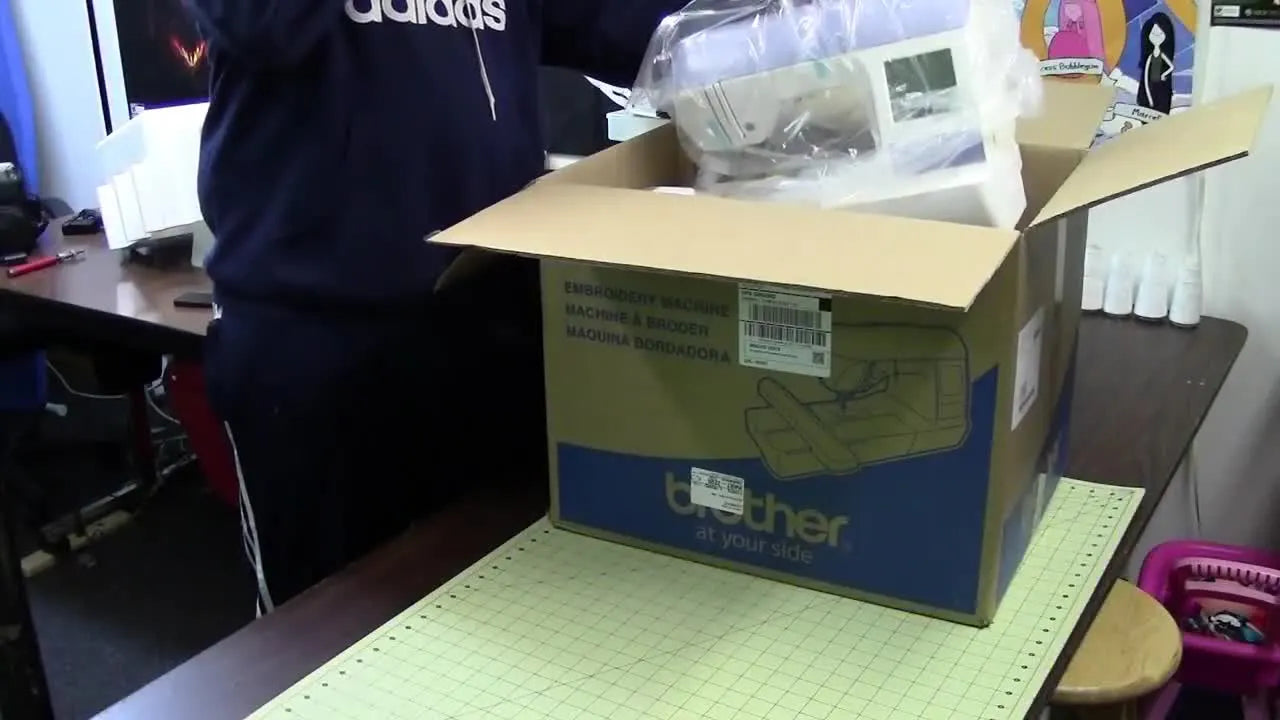 Person lifting Brother PE-770 embroidery machine from its cardboard box.