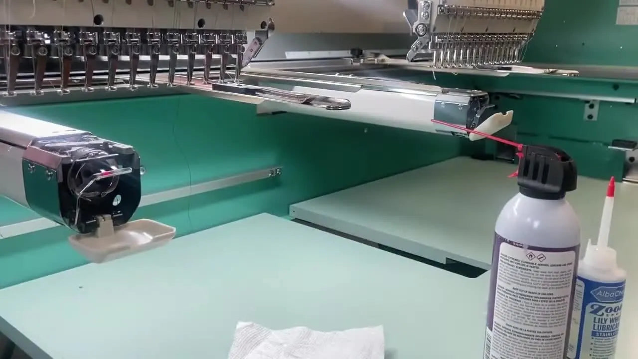 A close-up view of the exposed rotary hook assembly inside a commercial embroidery machine with the needle plate removed.
