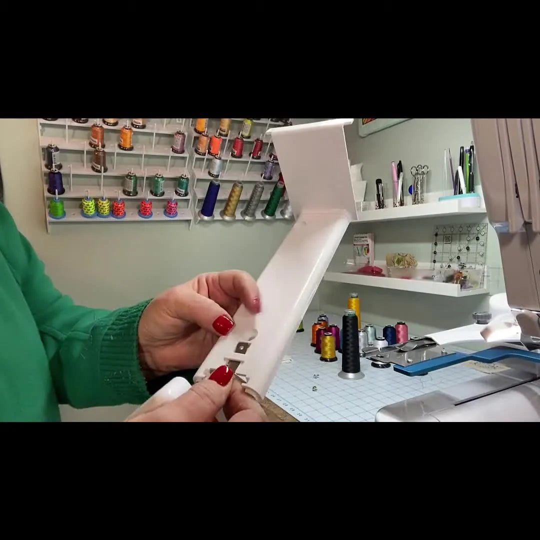 Close-up of the bobbin cover hinge being snapped back into place on the Baby Lock Array assembly.