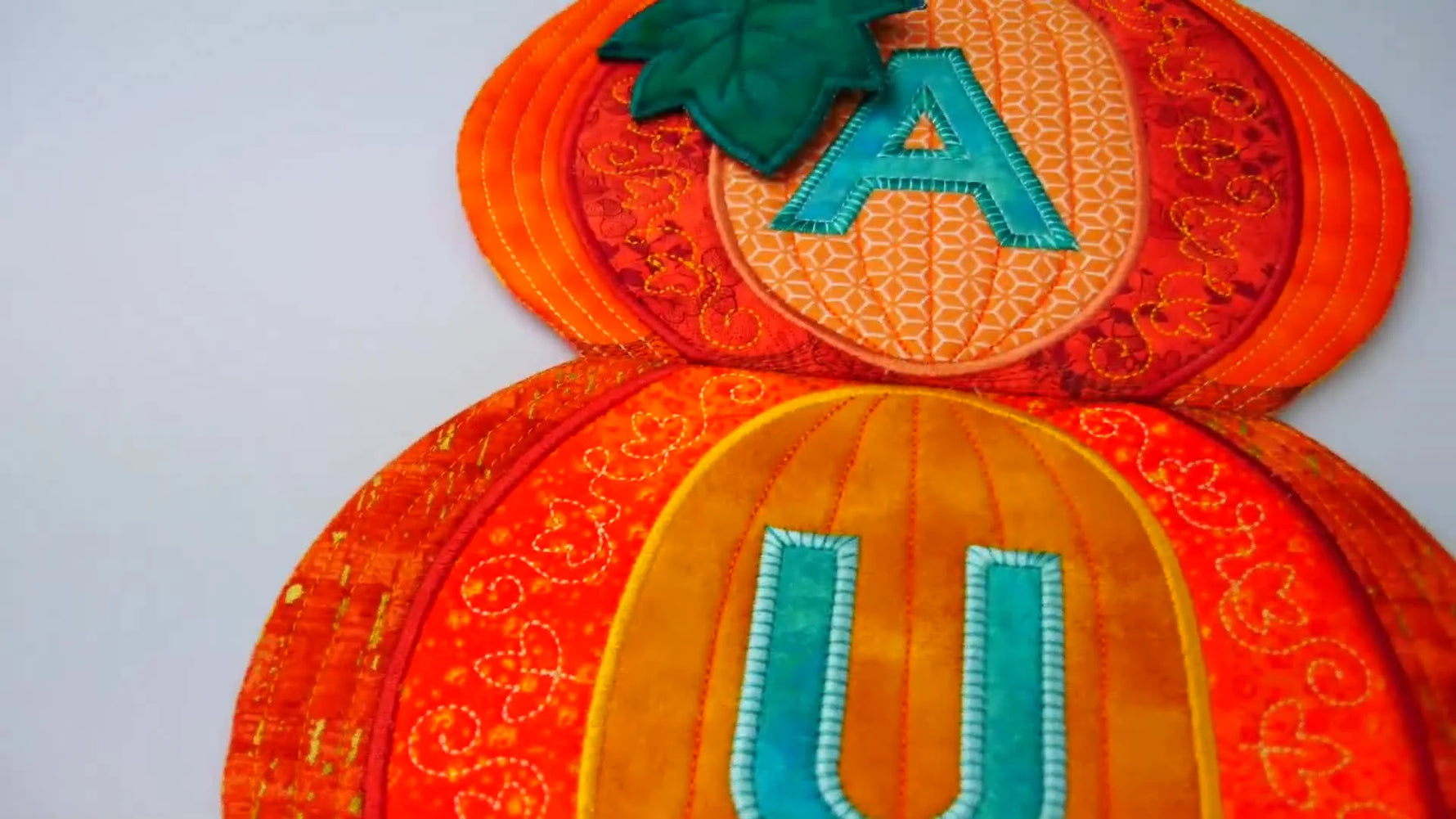 A finished pumpkin stack hanger with “AUTUMN” displayed on a wall, ready to hang with ribbon.