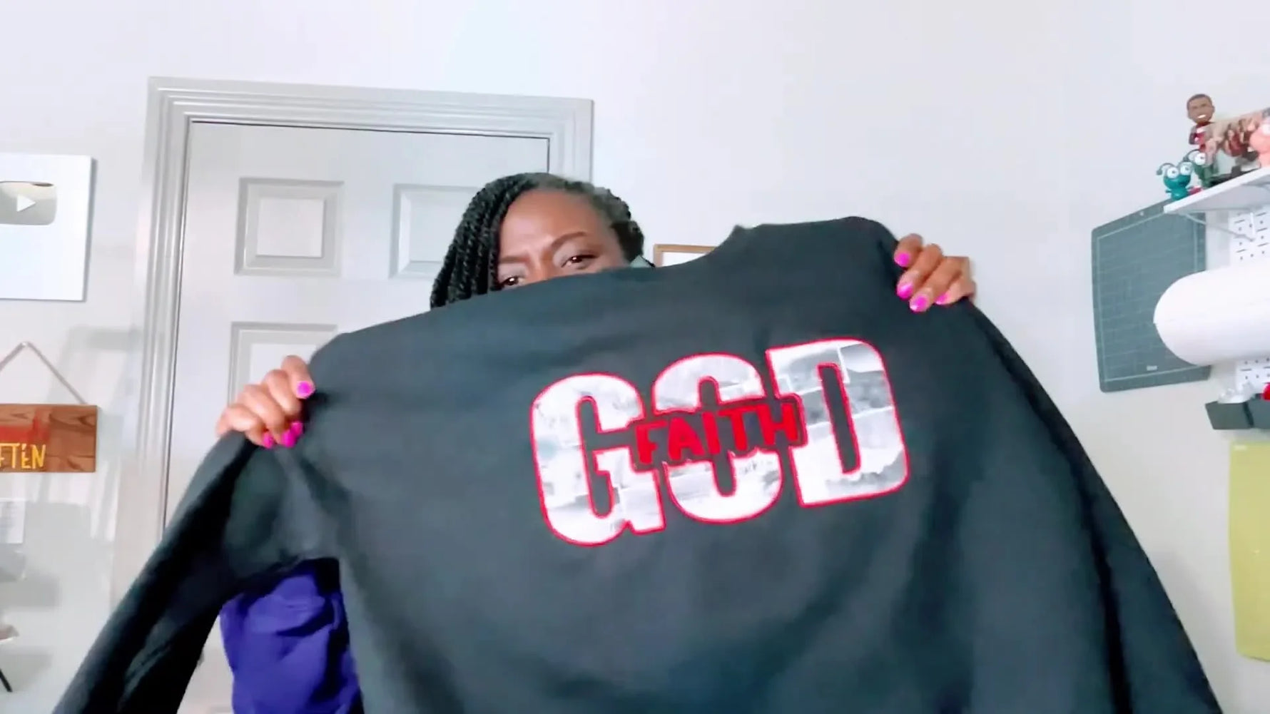 A finished black sweatshirt featuring a chest appliqué word design and a bold red side bow appliqué.