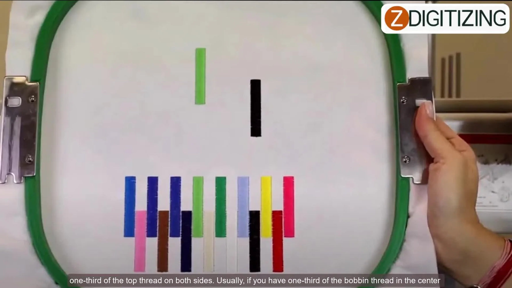 Hand adjusting a tension knob on the embroidery machine's thread path.
