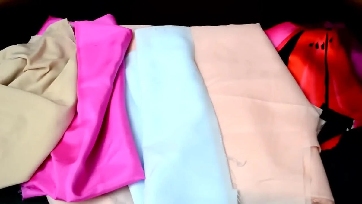 Hands arranging colorful rolls of lining fabrics.