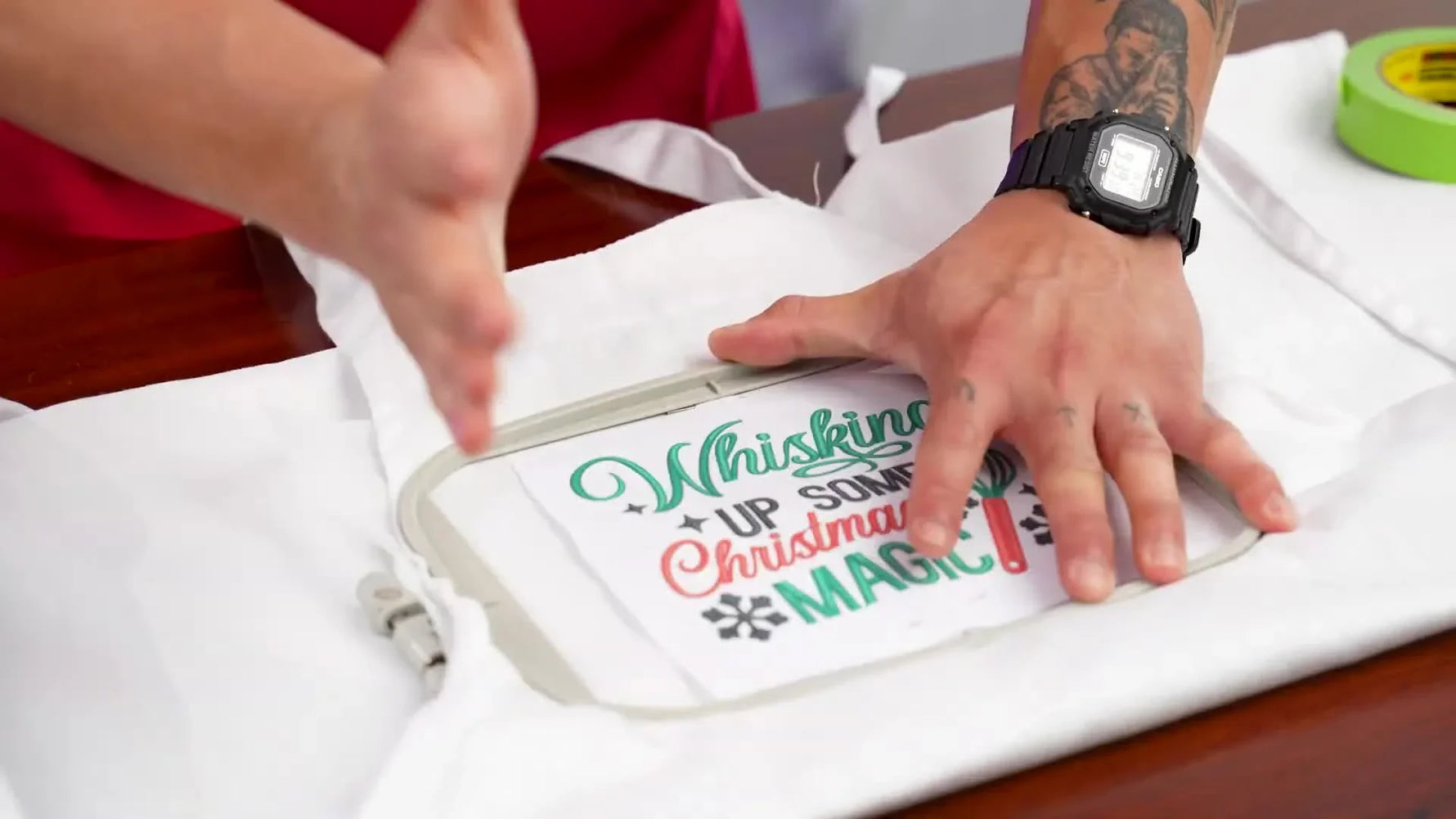 Both hands pressing the outer embroidery hoop down over the apron and inner hoop.