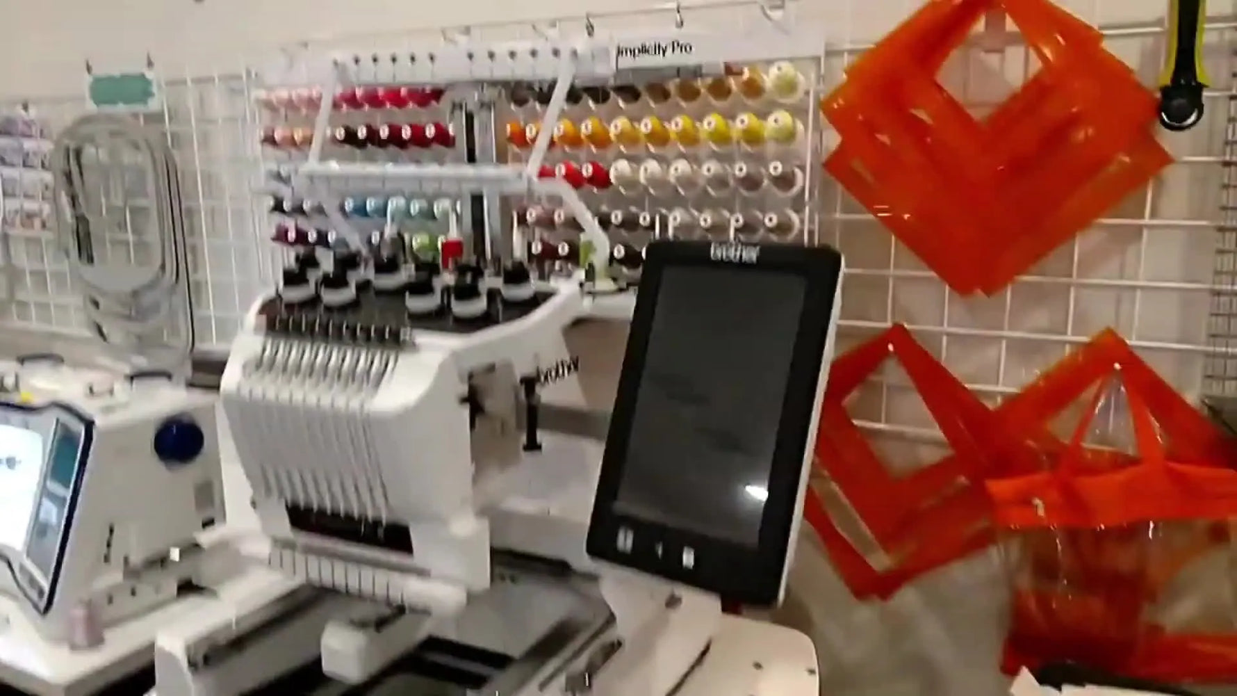 A Brother multi-needle embroidery machine set up in the Kimberbell testing lab, surrounded by thread and a production-style workstation.