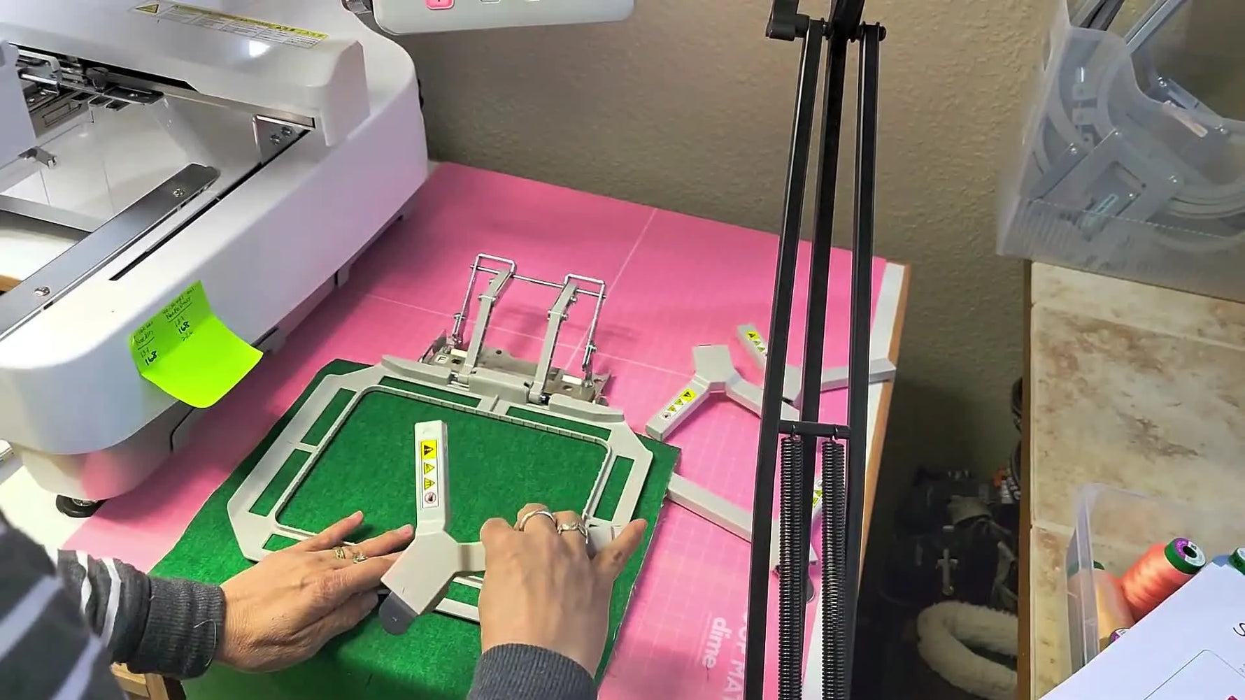 An overhead view of pressing the top magnetic frame onto the bottom frame to secure the fabric and stabilizer sandwich for embroidery.