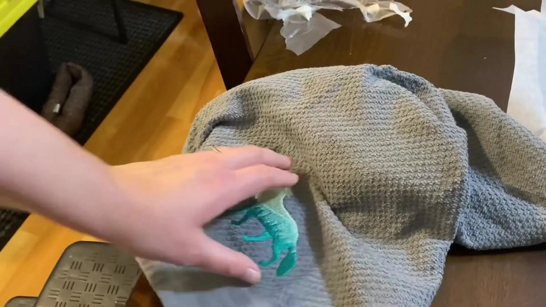 A close-up of the finished multicolor wolf embroidery stitched on a grey textured towel, showing crisp edges and a smooth gradient from light green to dark teal.