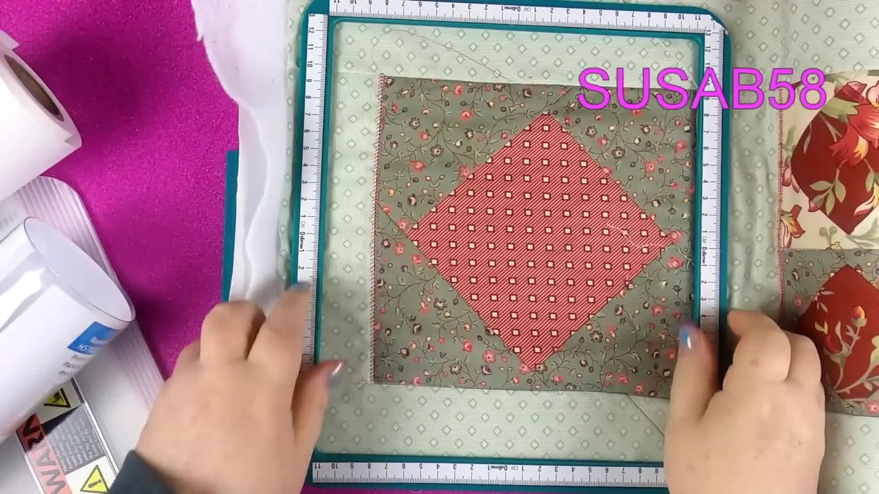 Hands lower the magnetic top frame onto a thick quilt sandwich as the Snap Hoop Monster snaps into place.