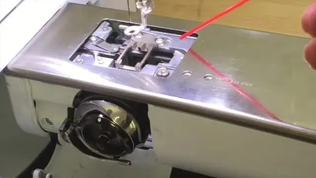 A close-up shows the red straw of a compressed-air can aimed from the back of the stitch-plate area toward the front opening to blow lint outward.