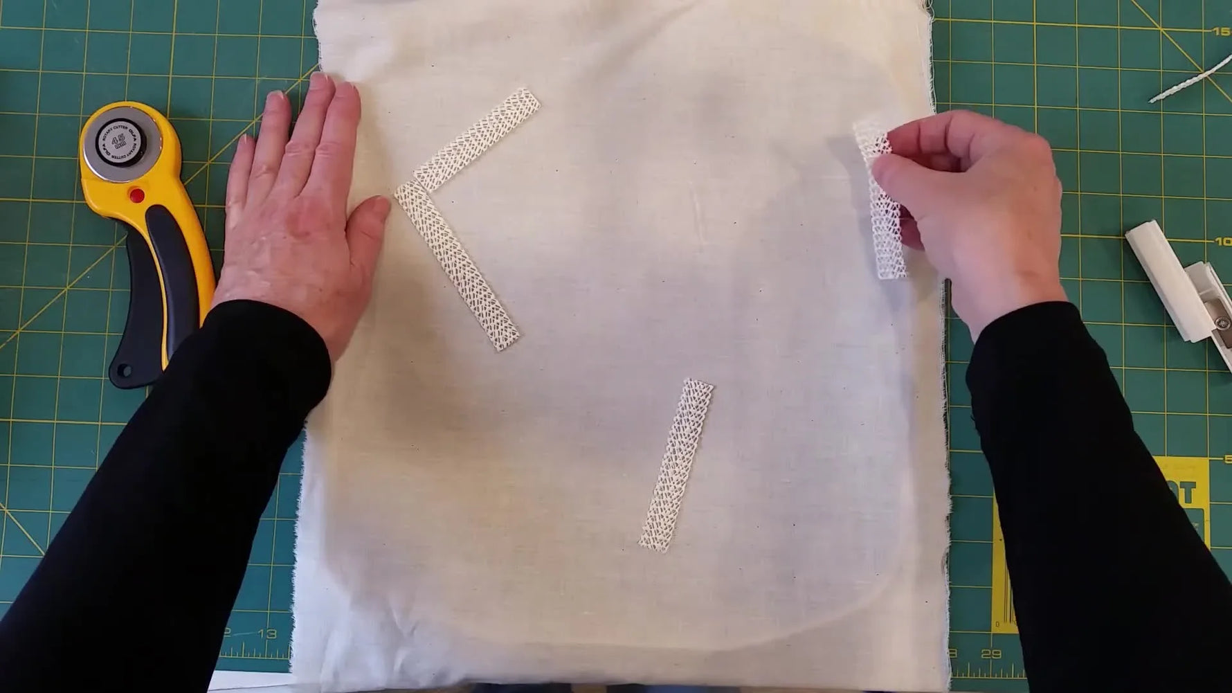 Overhead view of rubberized matting strips placed on fabric inside a large hoop to increase grip and prevent shifting.