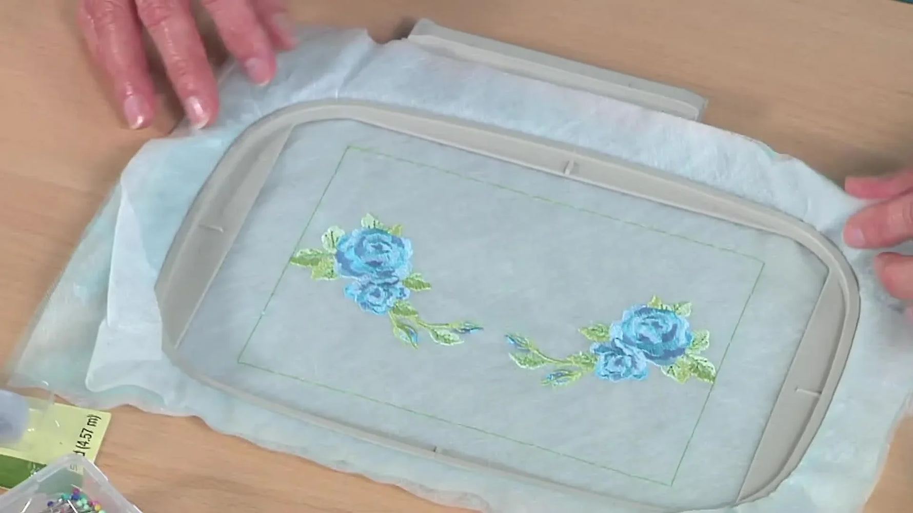 A hooped water-soluble stabilizer sandwich with embroidered roses, ready to be trimmed into a soft patch for a slinky knit neckline.