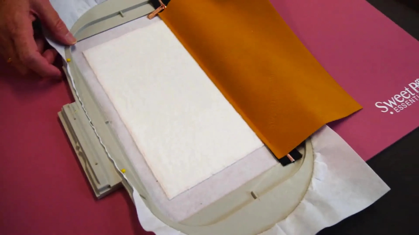 An orange PU leather piece with a zipper is hooped in an embroidery frame, showing the exact in-the-hoop scenario where pressing space is limited.
