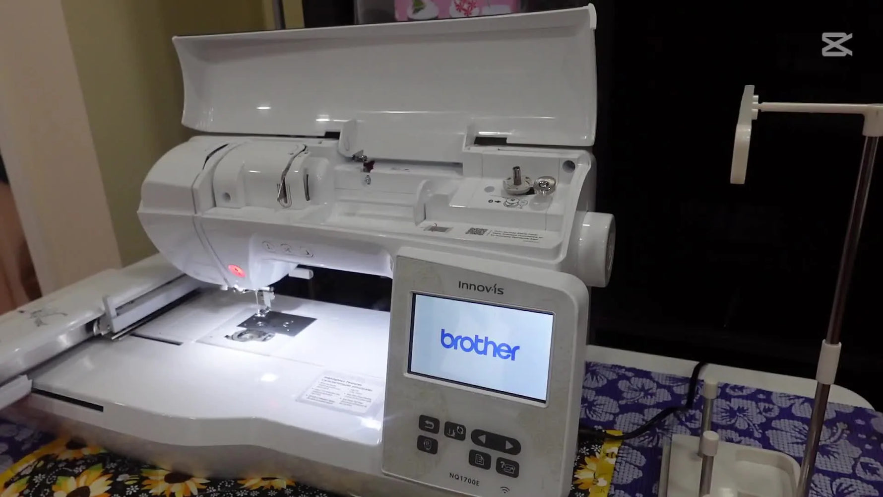 A wide view of the Brother Innov-is NQ1700E set up on a workspace with the lid open, ready for a first embroidery run.