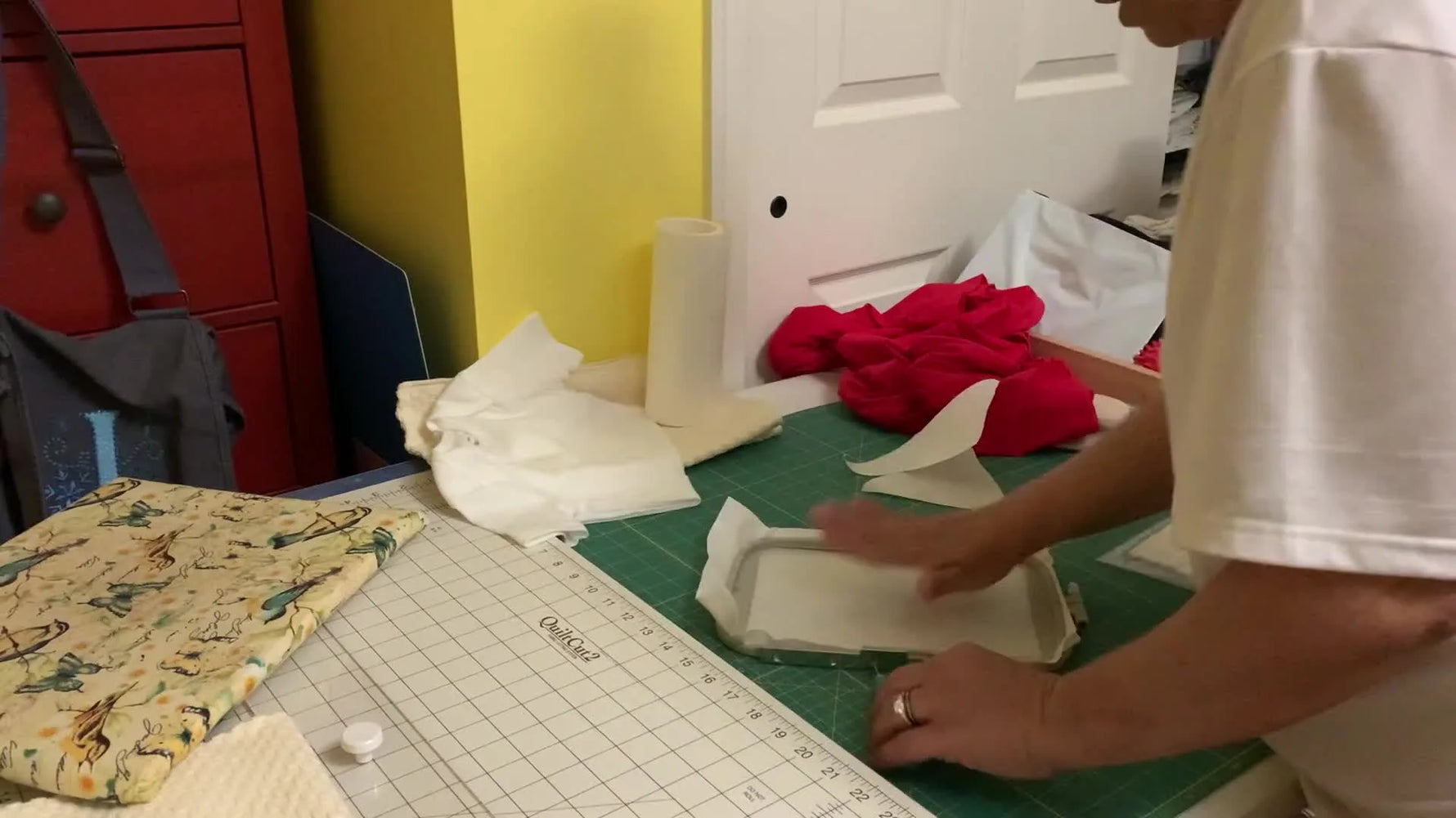 A close-up of peeling the paper layer off sticky stabilizer inside a 5x7 hoop to reveal the adhesive surface for floating garments.