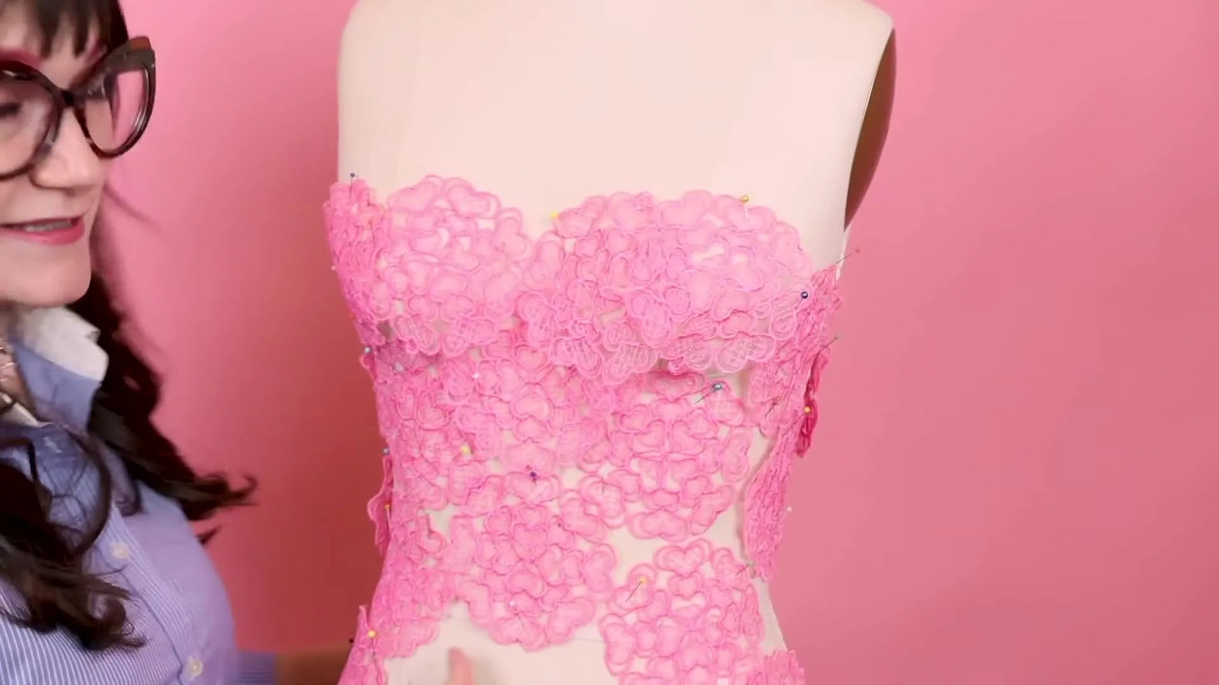 A dress form displays a pink lace bodice built from multiple freestanding lace heart motifs pinned into place.