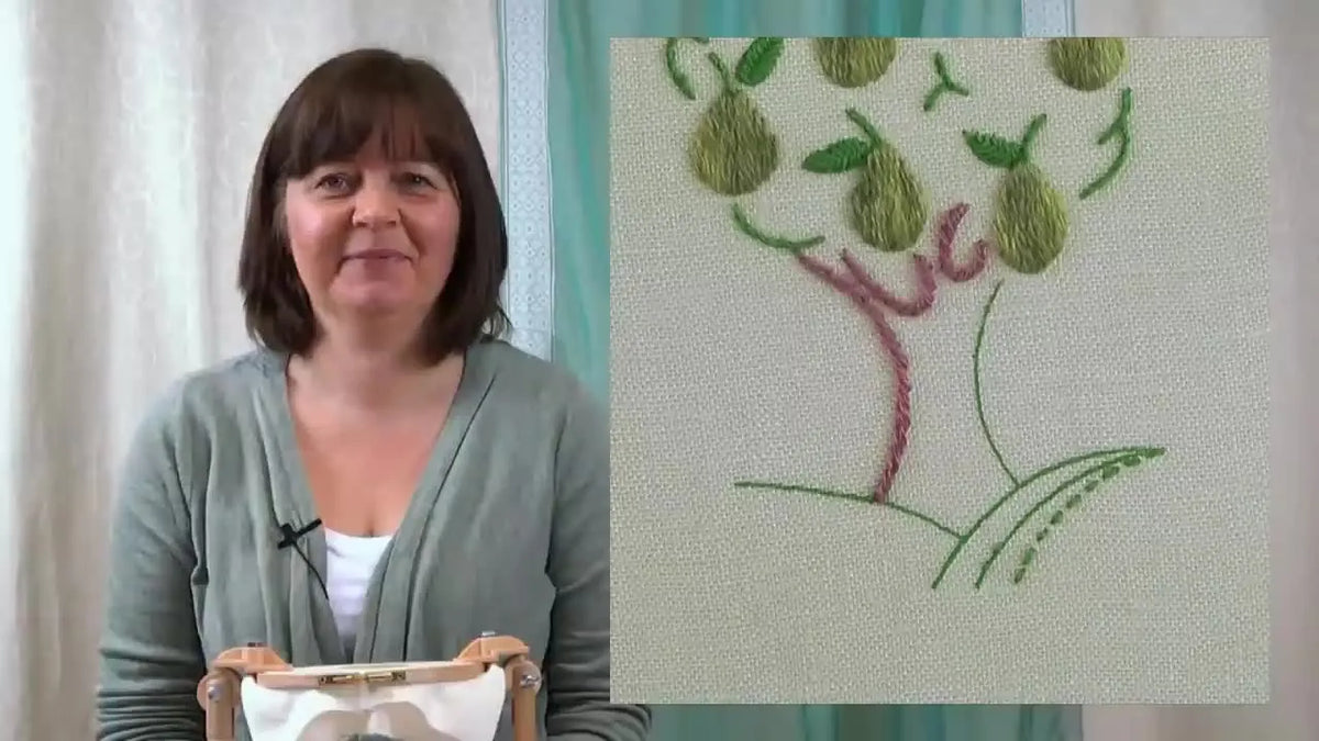 Instructor demonstrating rope stitch embroidery with completed pear tree embroidery.