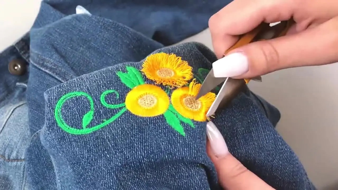 A wide comparison shot of three sunflower embroideries on a denim jacket—one looped fringe, one shaggy hair effect, and one flat—showing the texture difference clearly.