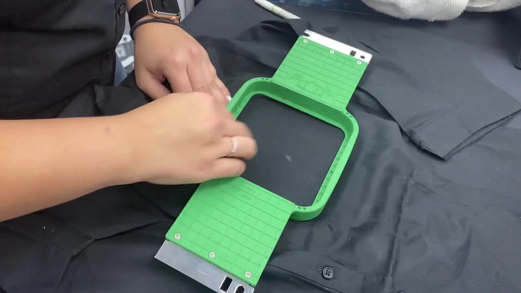 A green grid-style hoop is aligned so the shirt’s white placement mark sits exactly on the hoop’s zero crosshair.