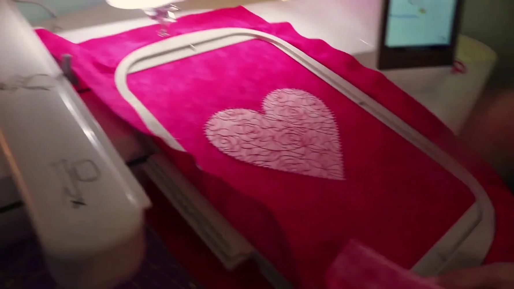 The finished heart appliqué sits in the hoop with a rose-fill interior and a star-motif border, ready to become a pillow panel.