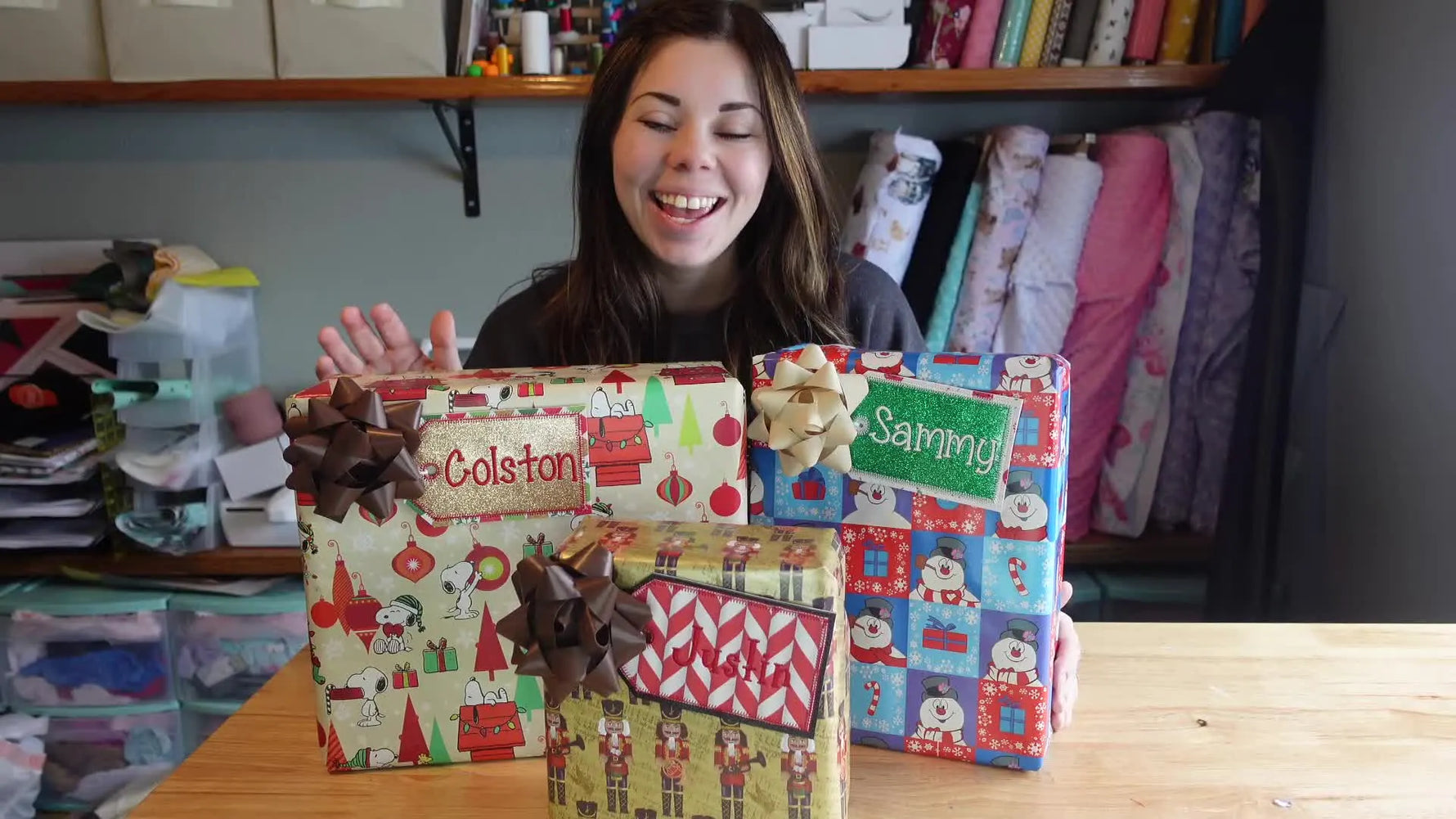 Woman presenting three wrapped gifts with personalized embroidery tags.