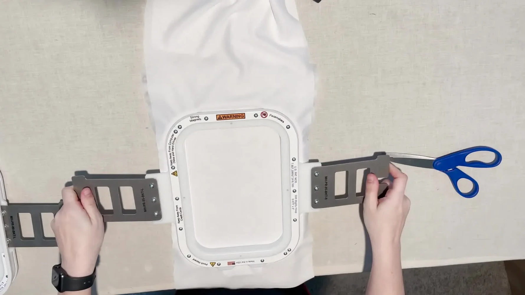An overhead shot capturing the moment the top magnetic ring snaps onto the bottom frame, clamping fabric and stabilizer securely.
