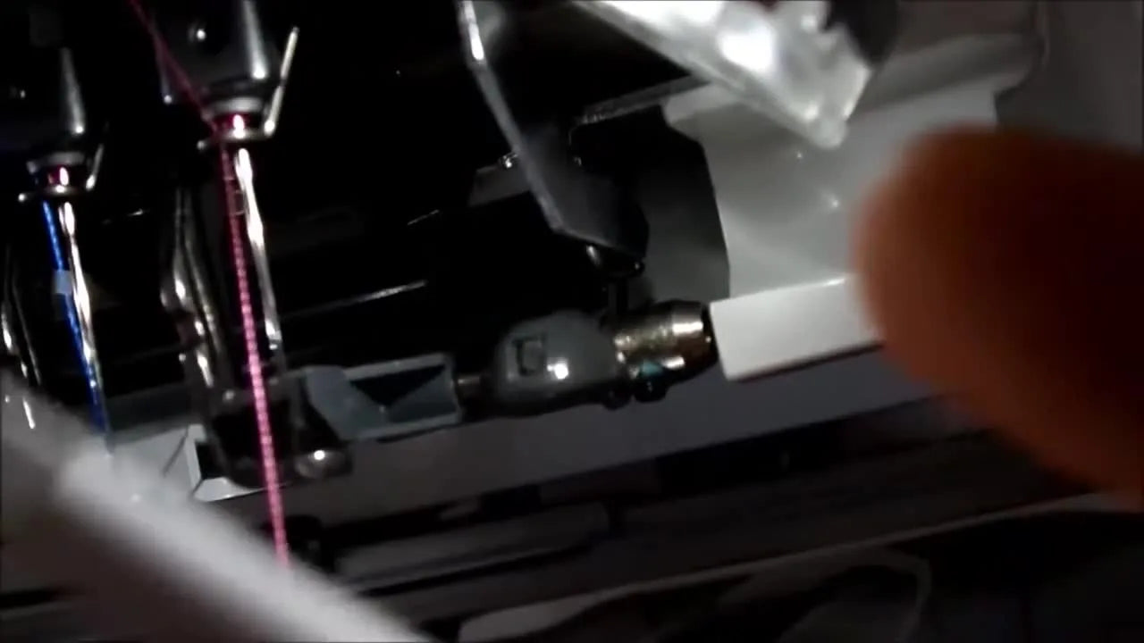 Close-up of the Brother PR-650 automatic needle threader as the white helper tool pushes thread behind the wire bar for a clean, reliable thread-through.