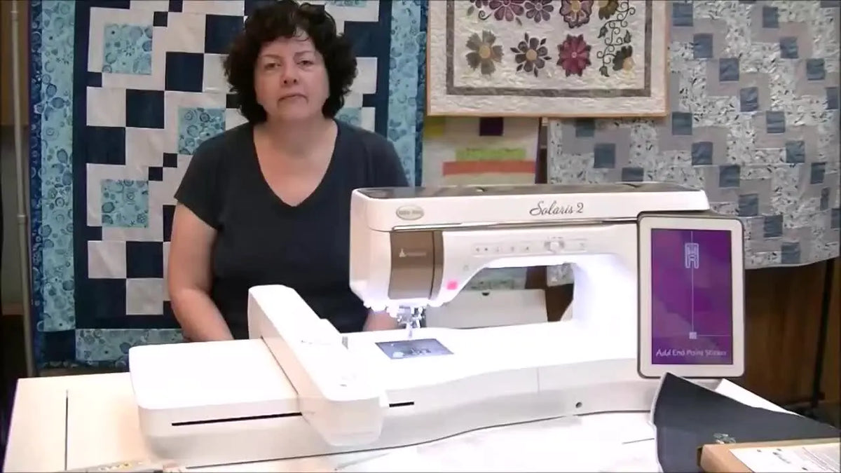 Presenter introducing Baby Lock magnetic embroidery hoops beside the Solaris 2 machine.