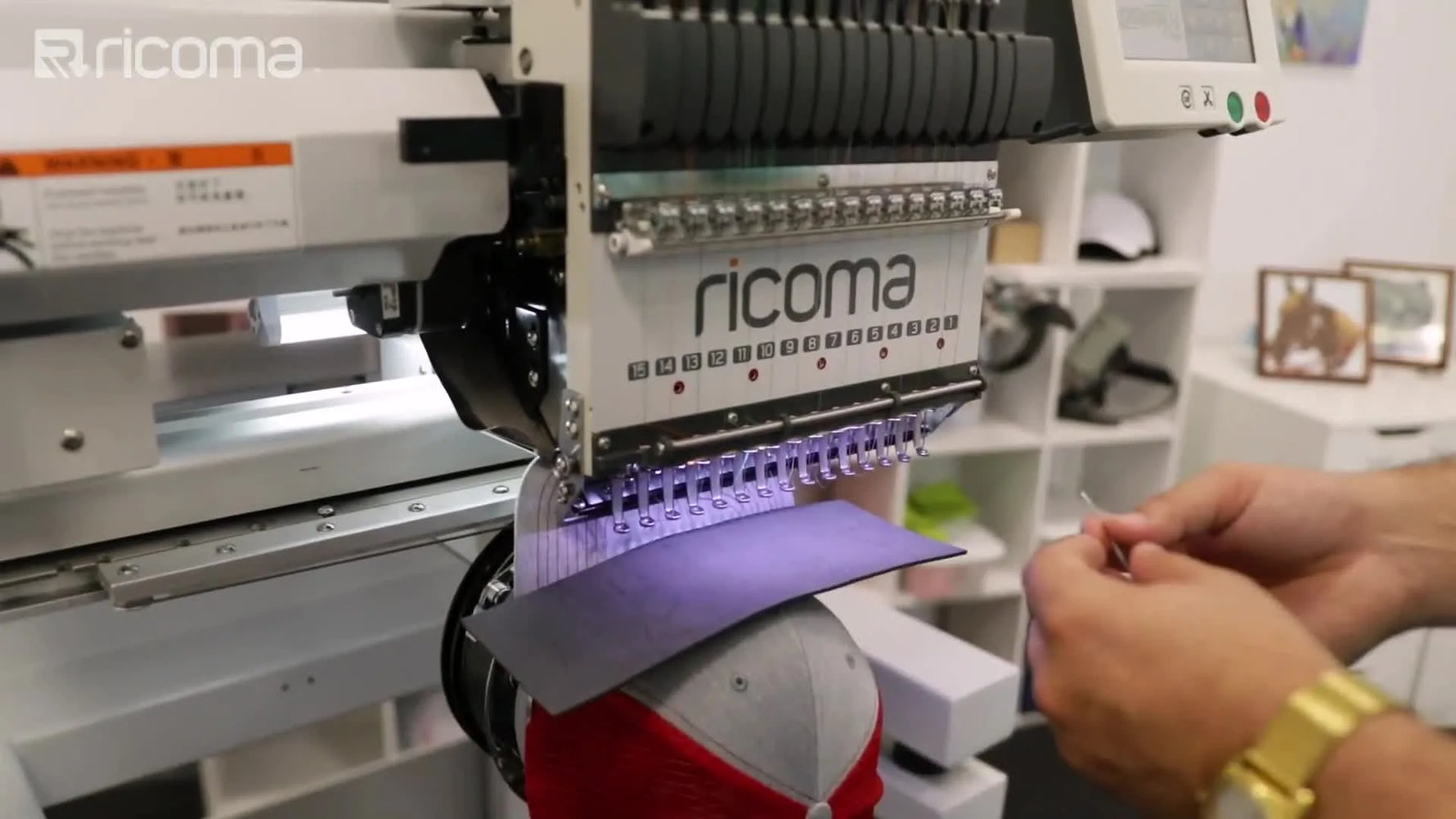 A high-angle close-up shows a multi-needle machine stitching a bold 3D puff logo over black foam on a hooped cap.