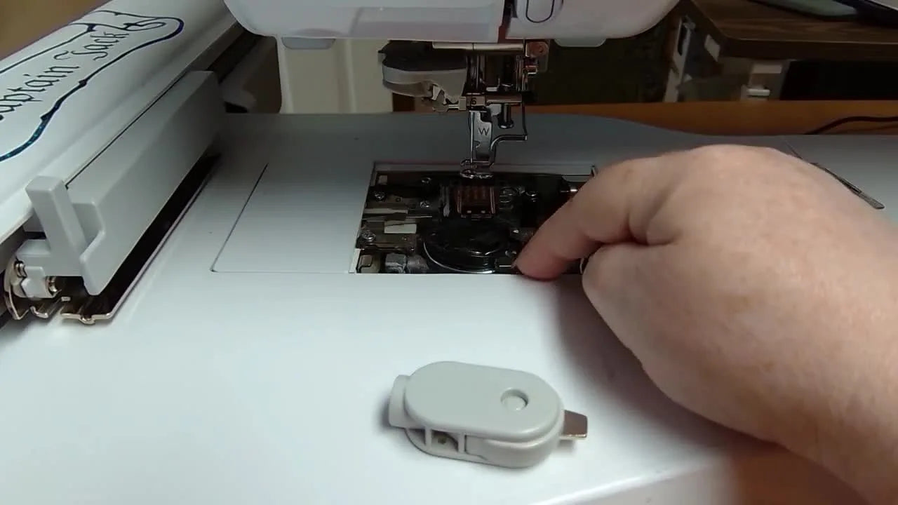 A close overhead view shows the bobbin case being aligned by matching the white arrow mark to the white dot on the machine race.