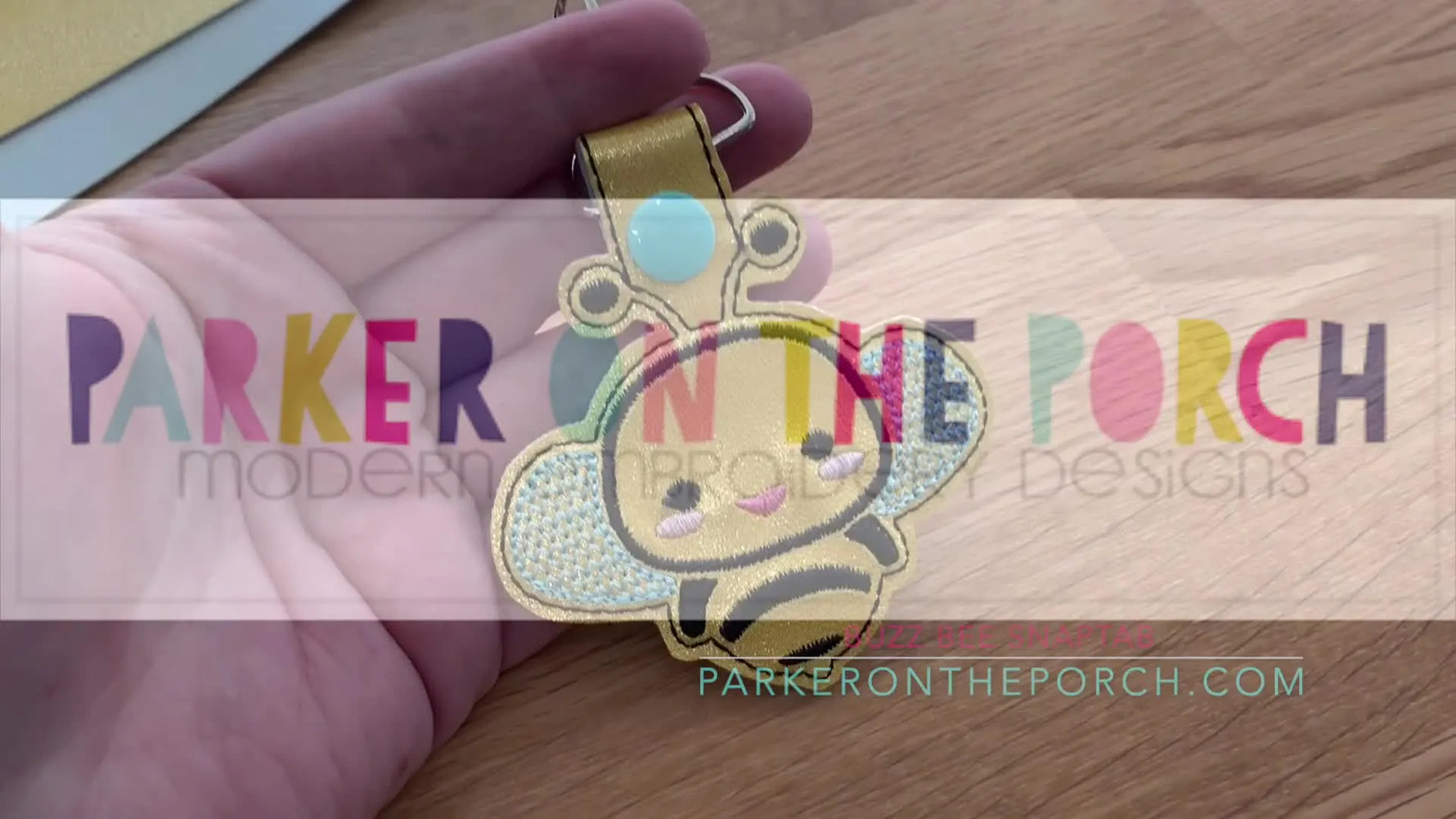 A close-up of the finished Buzz Bee snap tab keychain in metallic gold vinyl with installed hardware.