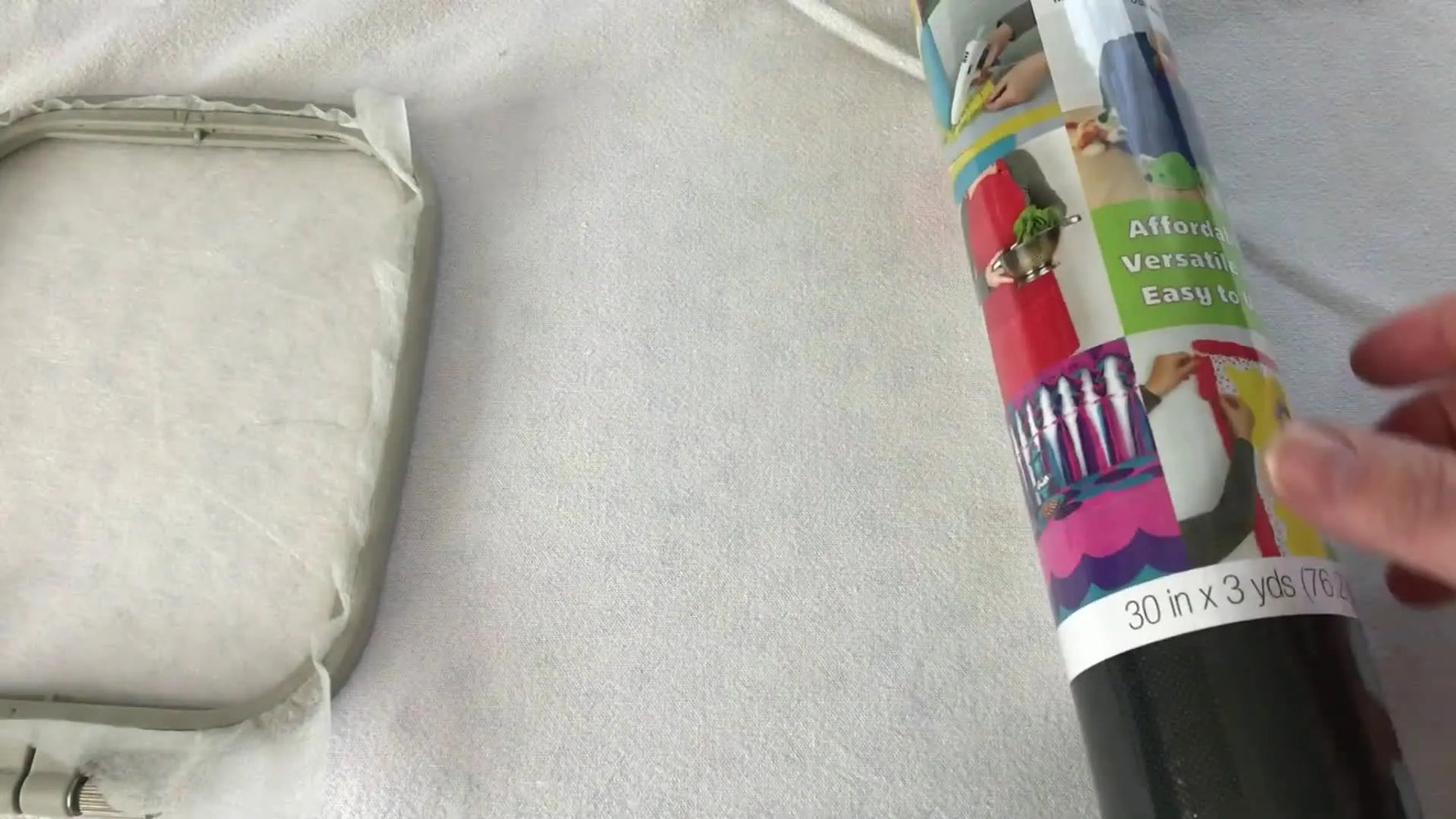 Two rolls of Fairfield Oly-Fun (black and white) sit beside a 5x7 embroidery hoop, highlighting a budget-friendly cutaway stabilizer alternative for test stitch-outs.