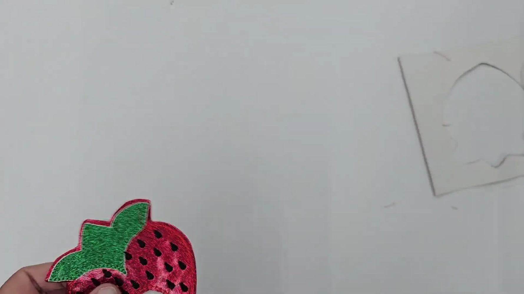 A finished glittery strawberry holder with a lollipop being inserted into the pocket opening.