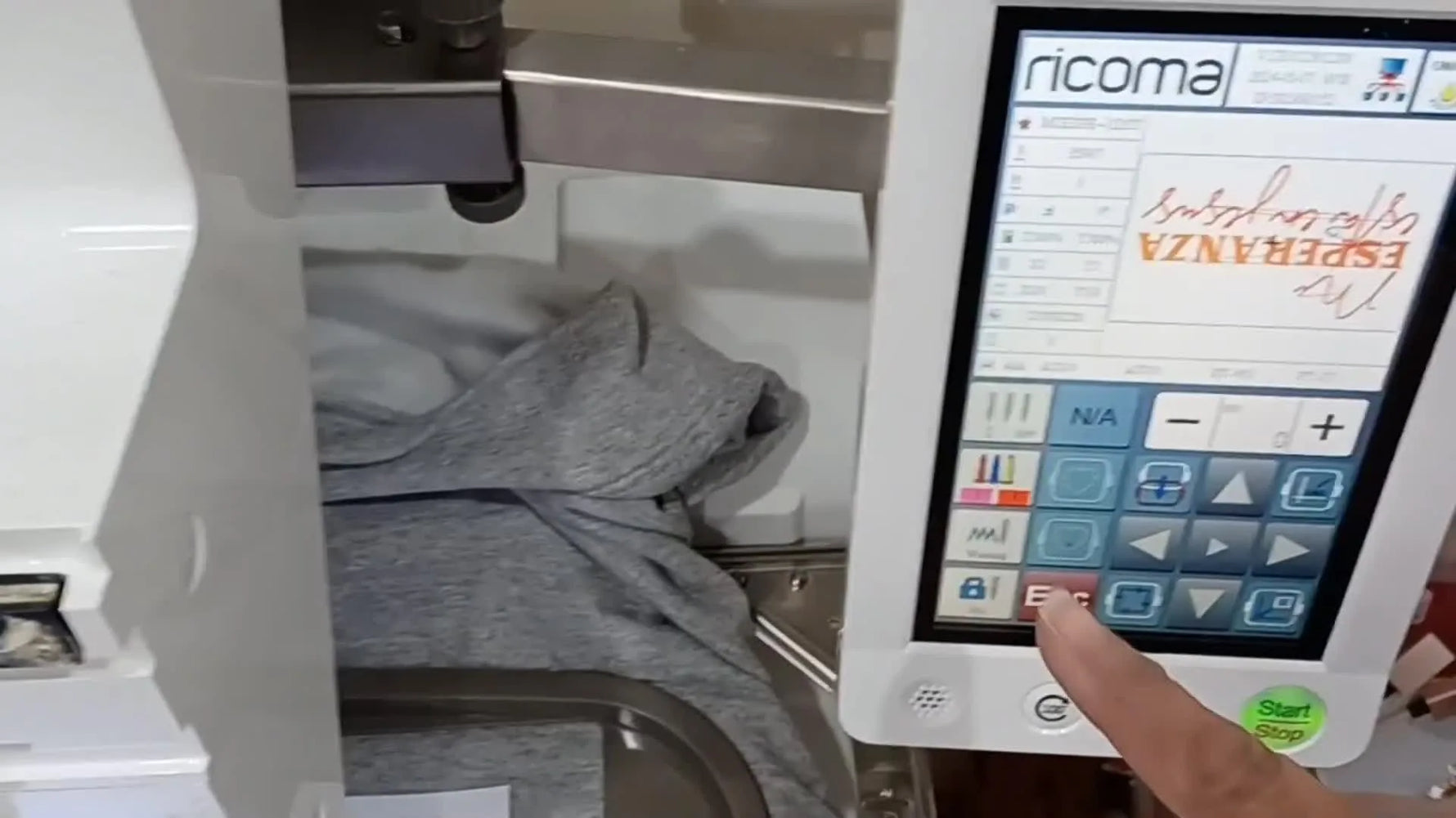 A close-up of the Ricoma EM1010 stitching red lettering at speed on a hooped grey sweatshirt.