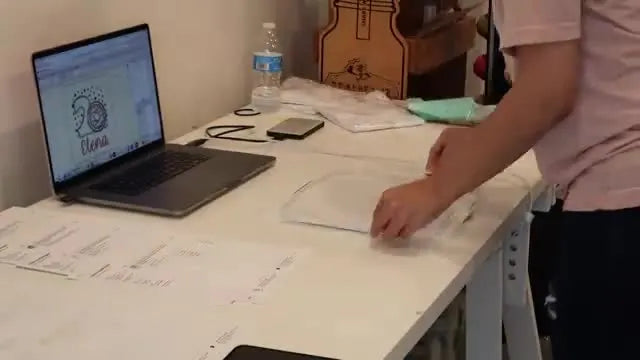 Hands close a magnetic 8x9 hoop over a shirt in a hooping station, showing the fast “snap” closure that speeds up production.