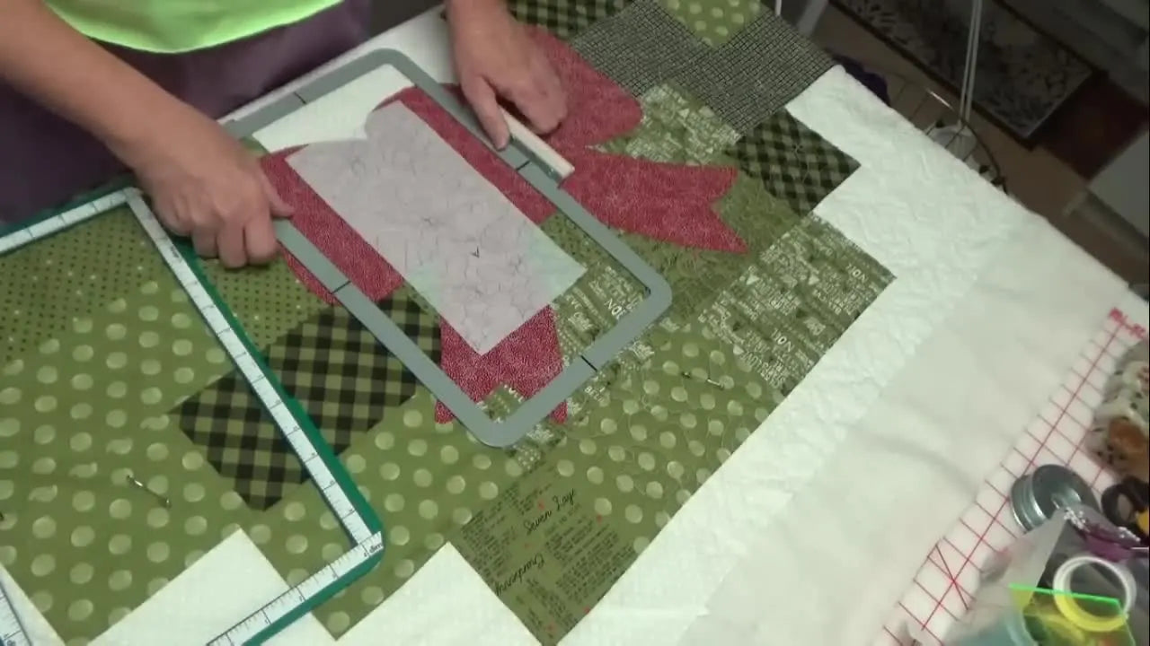 A thick quilt sandwich is clamped securely inside a large rectangular magnetic hoop with a paper alignment template visible in the stitching area.