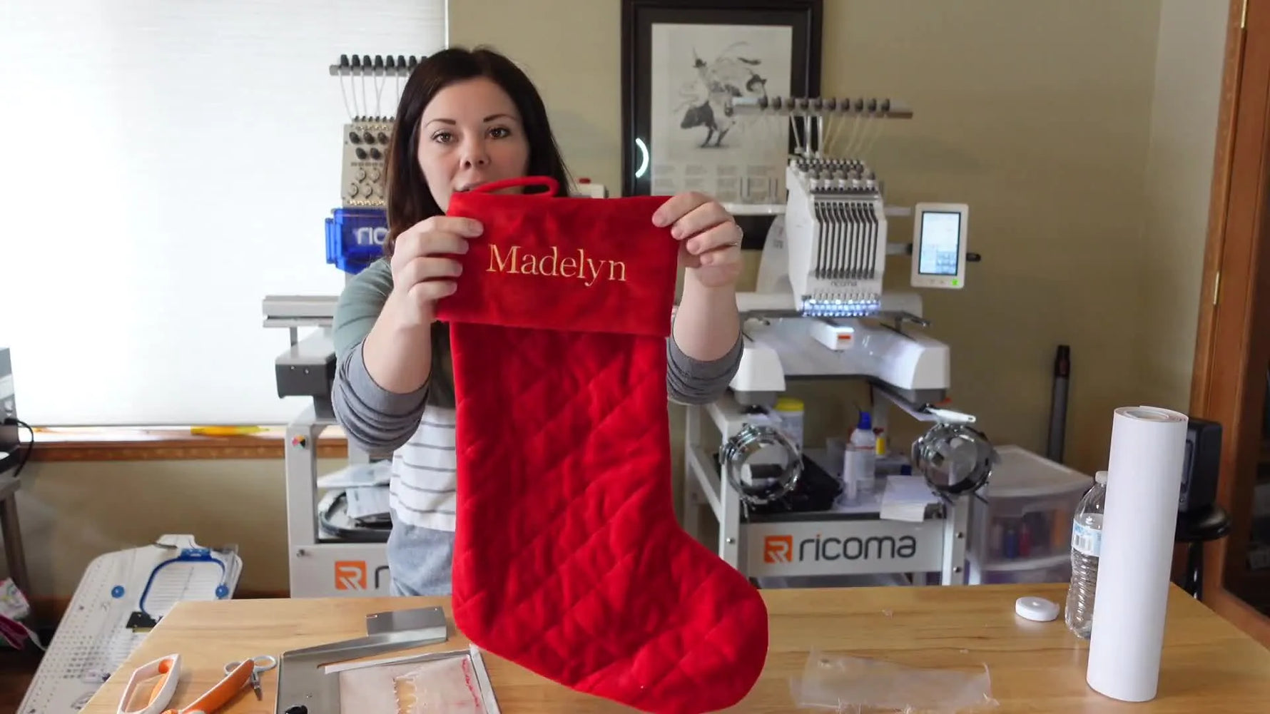 A finished red quilted stocking is held up with the name stitched in gold metallic thread, showing clean placement and smooth coverage on the cuff.