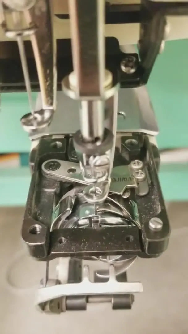 Macro view inside the rotary hook area showing the hook point positioned directly behind the needle for timing verification.