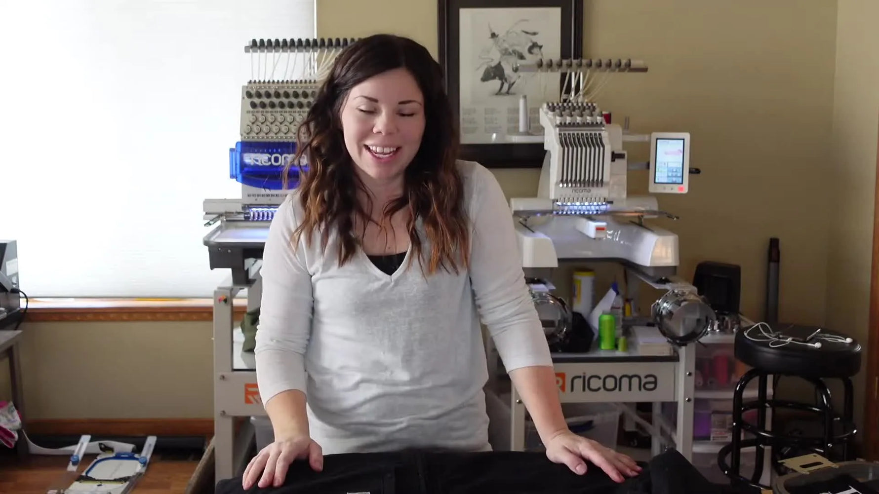 Woman standing with a black Carhartt jacket, preparing for embroidery.