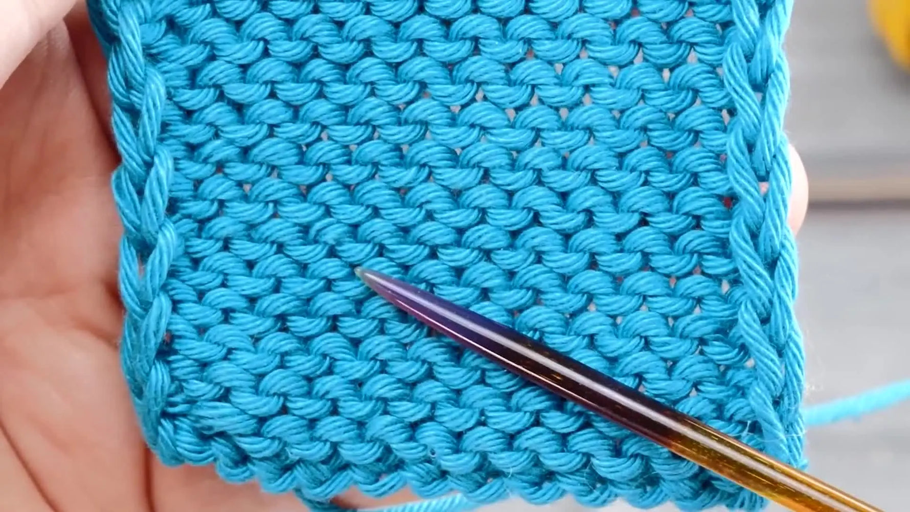 Close-up of the blue stockinette swatch showing one edge significantly looser than the other.