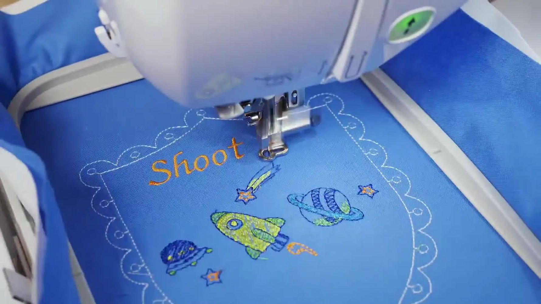 The finished “Shoot for the stars” shield design is shown in the hoop on blue fabric after stitching.