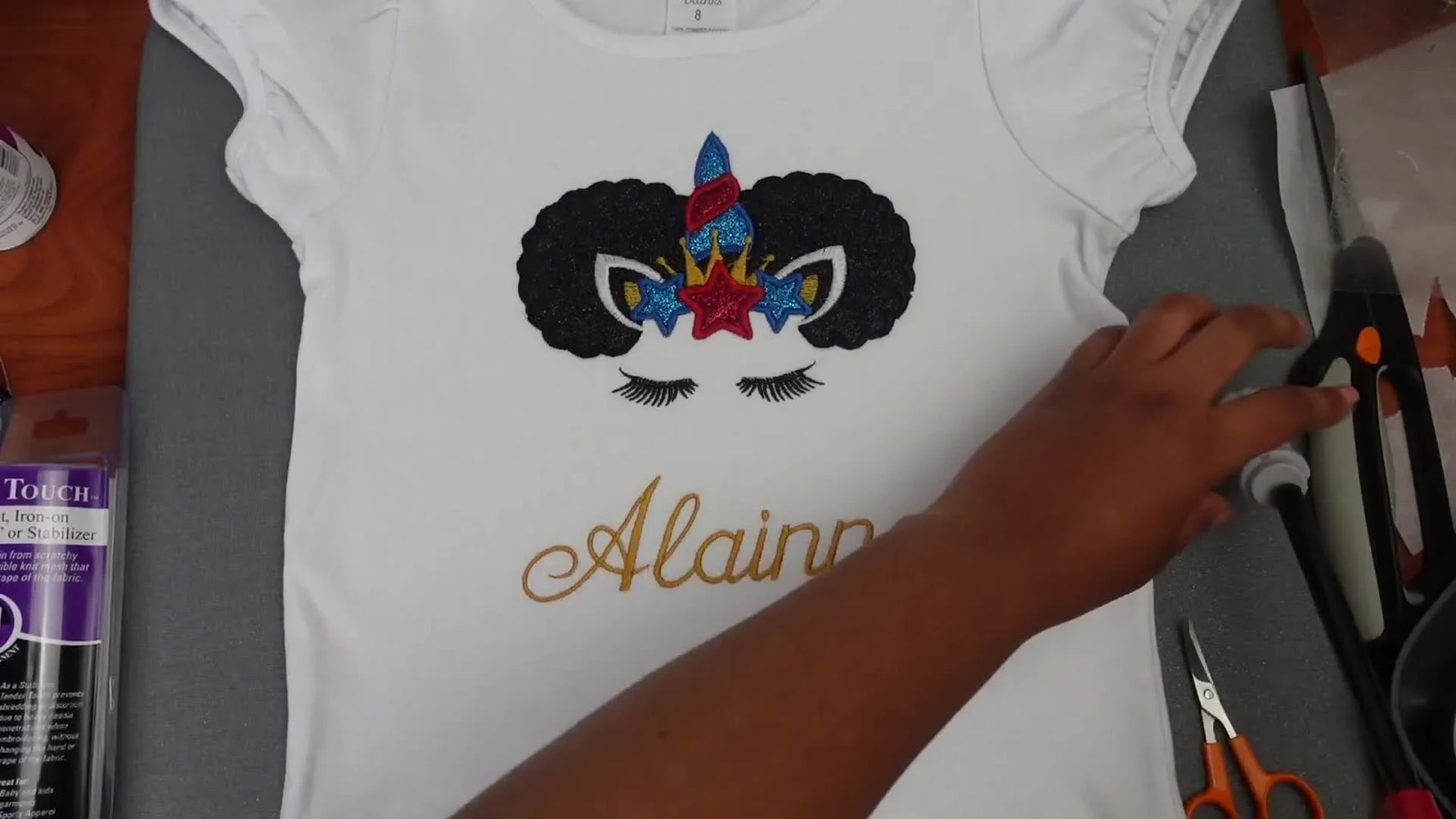Finished white t-shirt with an embroidered unicorn appliqué and name 'Alainna'.