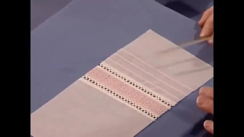 A close-up shows a serger forming a dense Shadow Pin Tuck while the fabric fold is guided precisely along the presser foot edge.