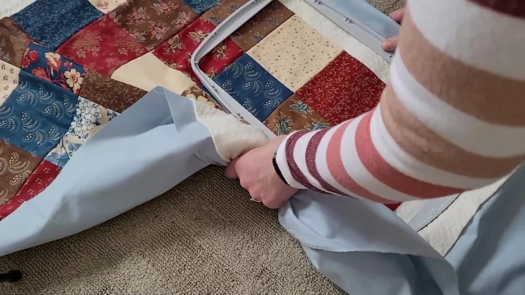 A close-up of pressing a standard 360x200 embroidery hoop closed over a thick quilt sandwich—the moment most people struggle with when quilting in the hoop.
