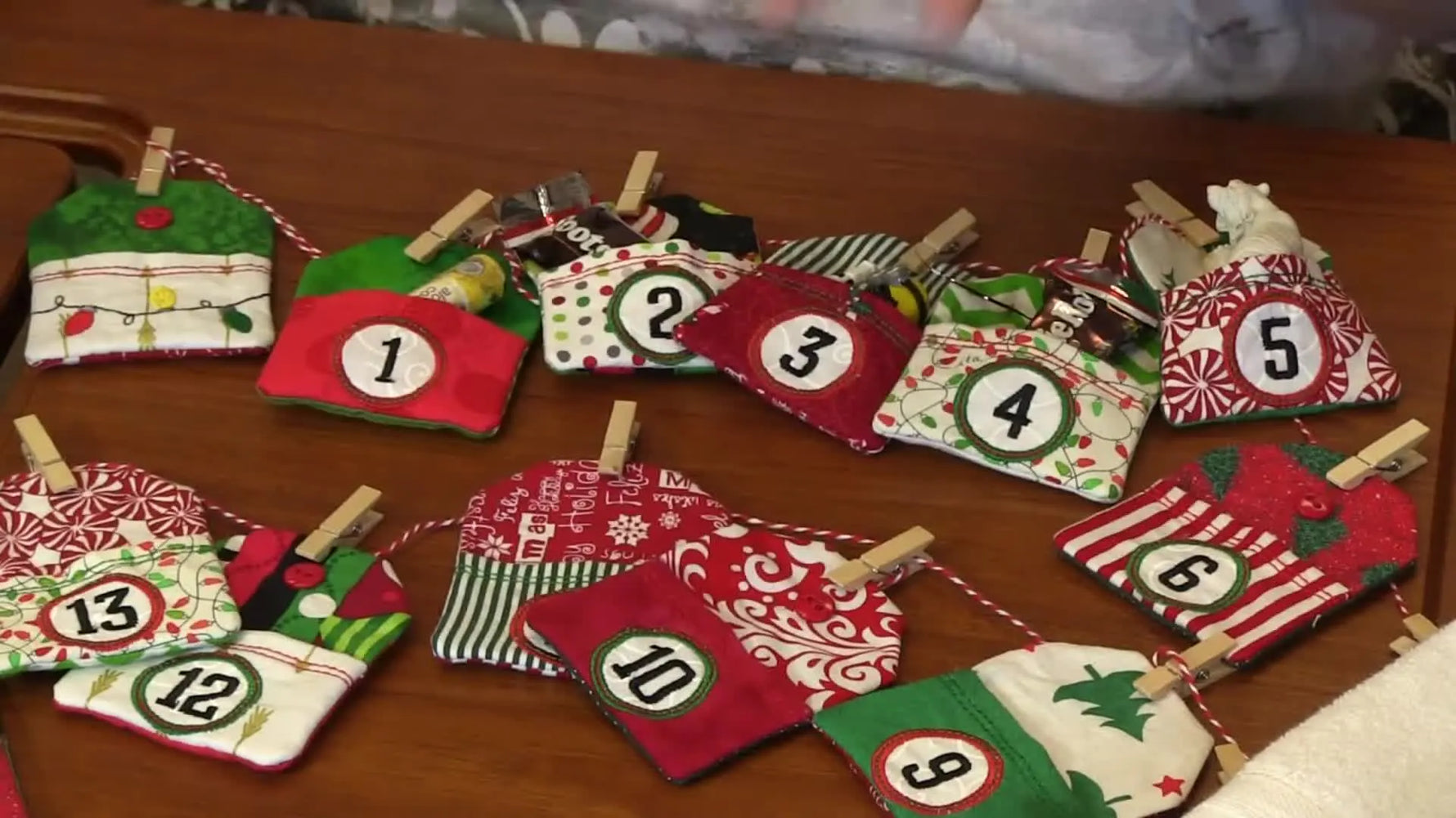 A colorful set of in-the-hoop pocket tags clipped to twine with mini clothespins, laid out like a reusable countdown banner.