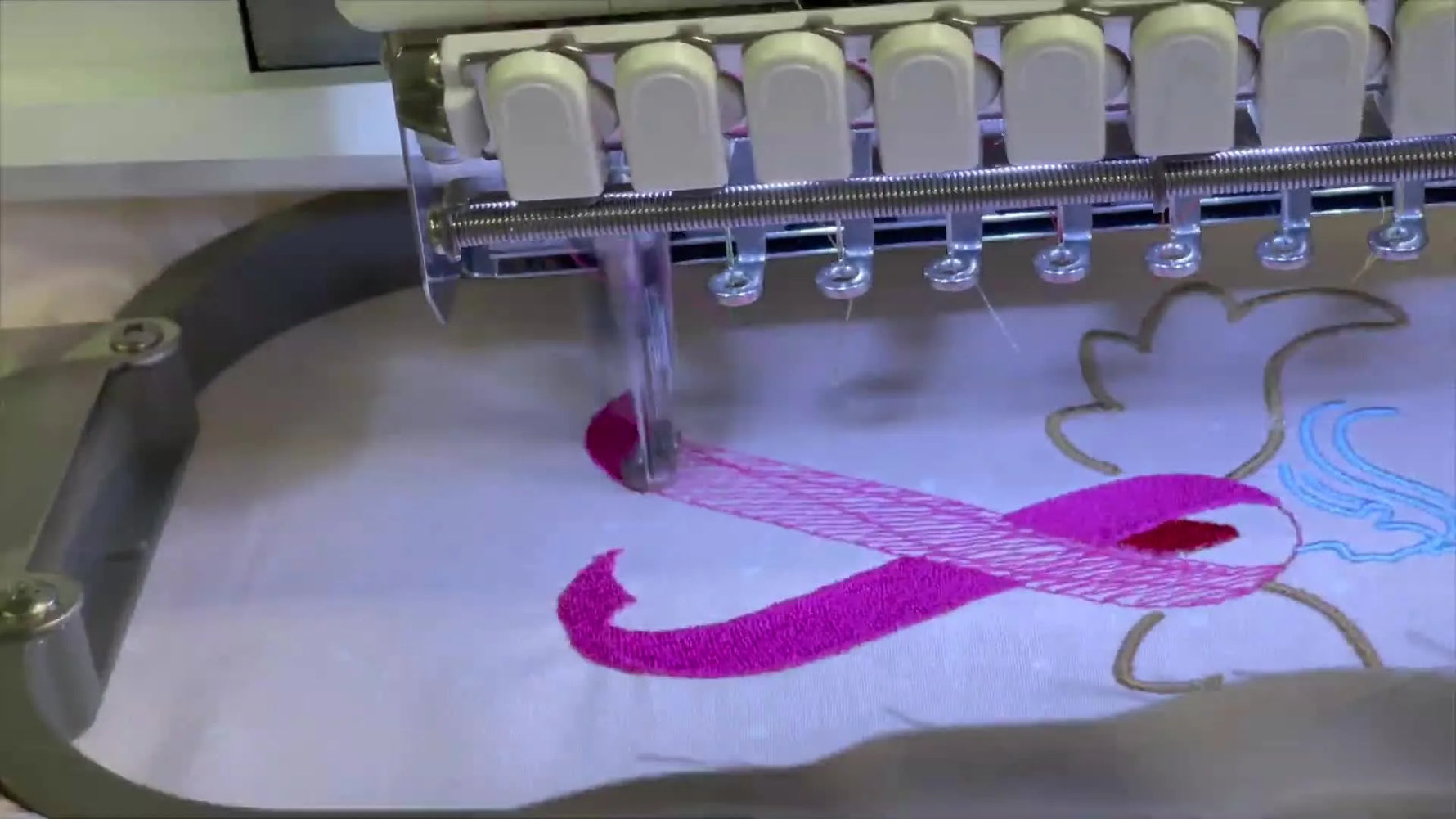The finished Pink Ribbon Angel design sits cleanly stitched in the hoop on the Ricoma EM1010, ready to unhoop and finish.