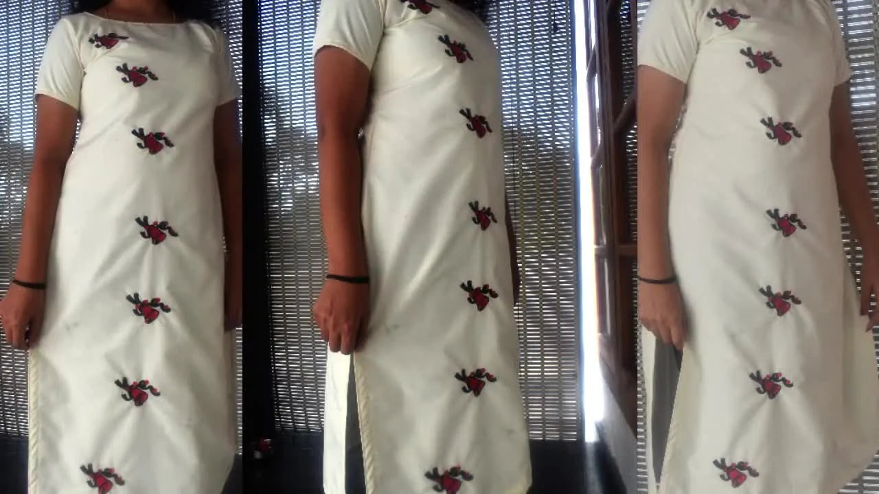 A finished white Churidar top is worn and modeled, featuring three vertically aligned Christmas bell embroidery motifs on the front panel.