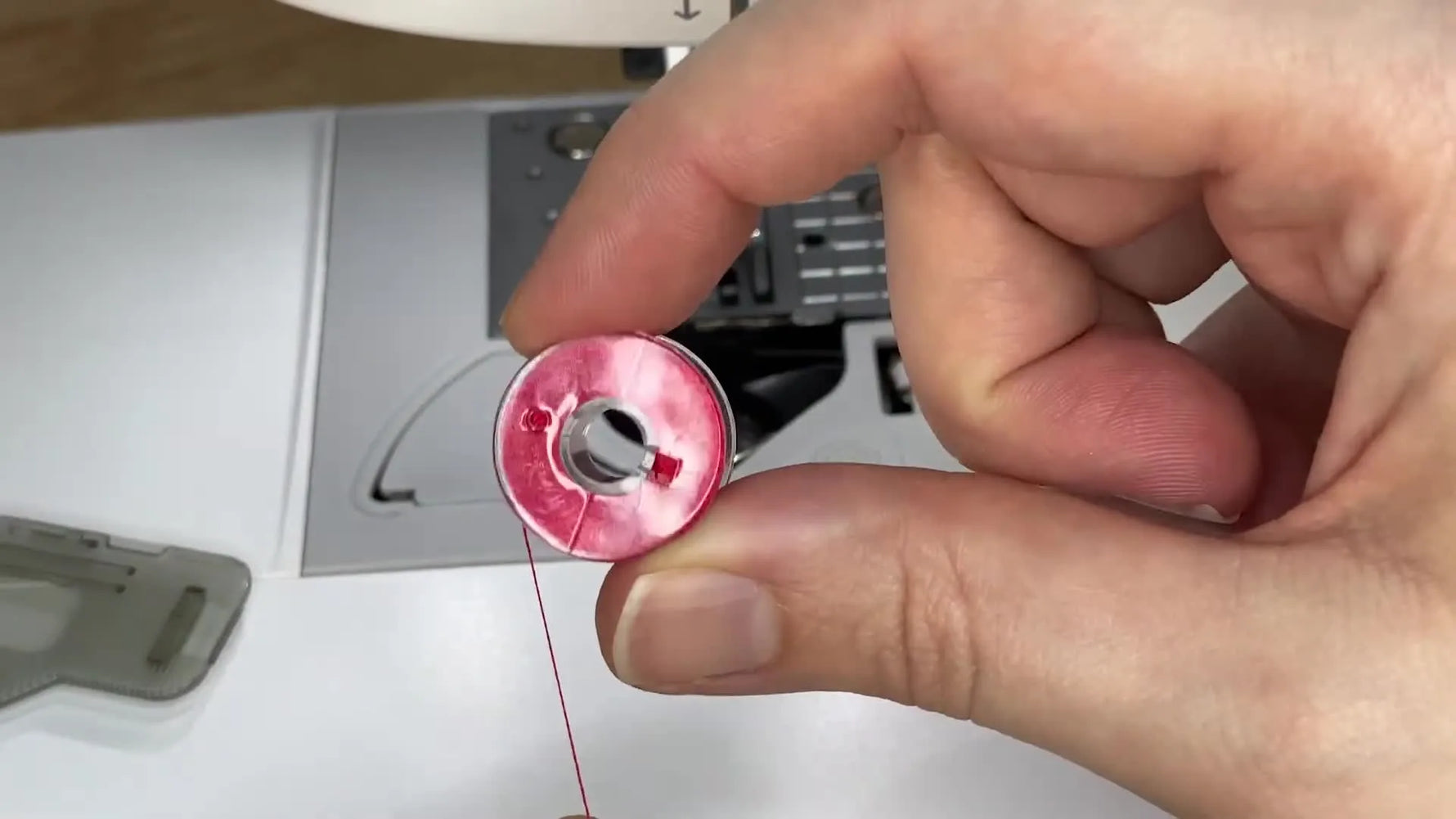 A close-up shows the correct “P” orientation for a Singer SE9180 drop-in bobbin so the thread feeds smoothly and the bobbin turns counter-clockwise.