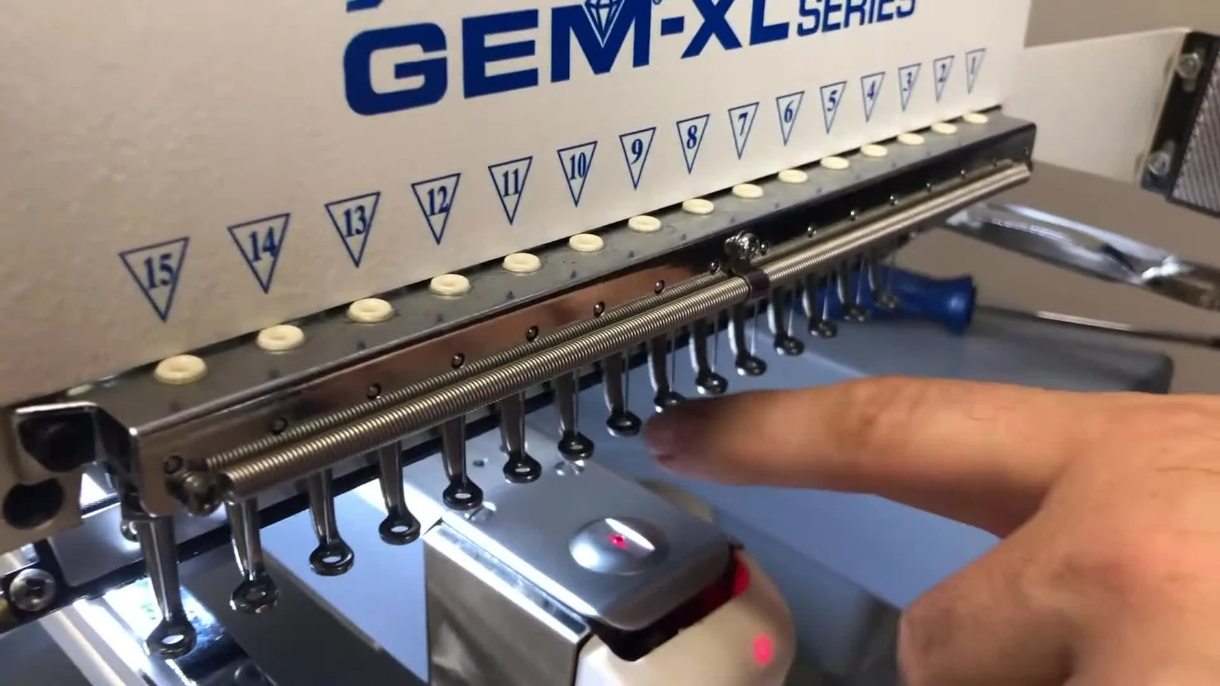 Hector lifts the Meistergram GEM 1500 XL needle case assembly off the rail with both hands, showing the safest removal posture and clearance.