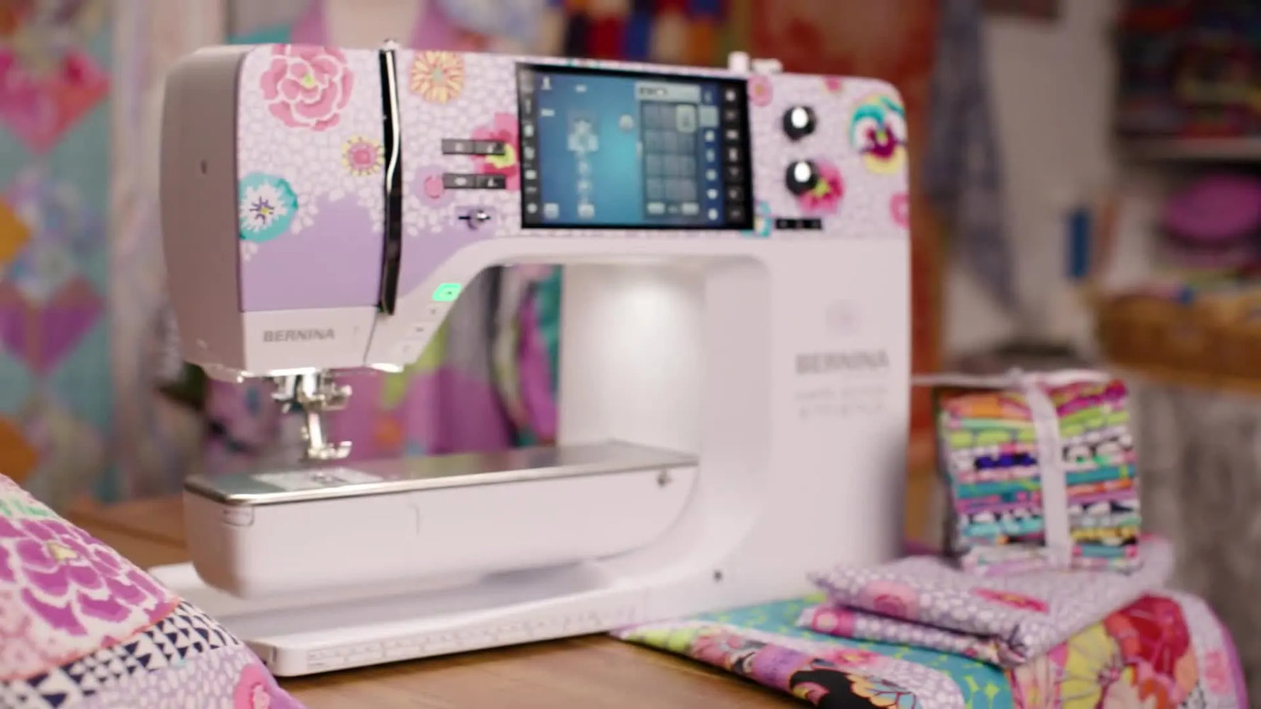 The Bernina B 770 QE PLUS Kaffe Edition sits ready beside coordinated fabric bundles, highlighting the machine’s color-forward design and embroidery focus.