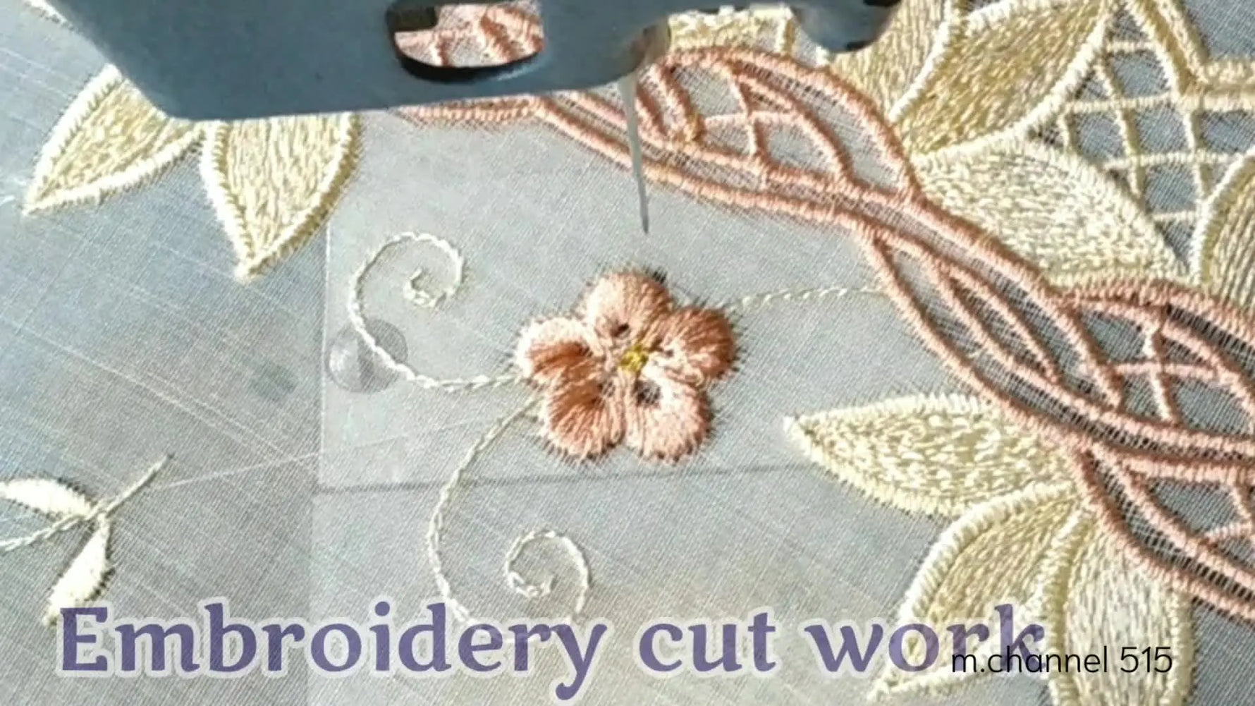 Close-up of an embroidery machine needle stitching a delicate floral design on sheer fabric, with already completed parts of the design visible.